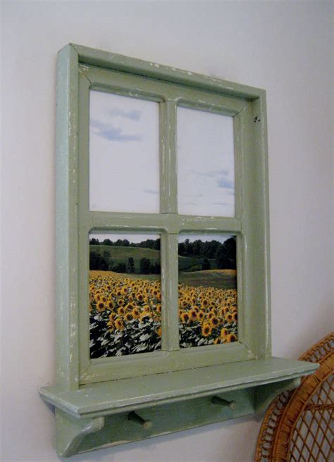 Set on the window pane is a faux wreath with green leaves and cotton. . Fake window frame
